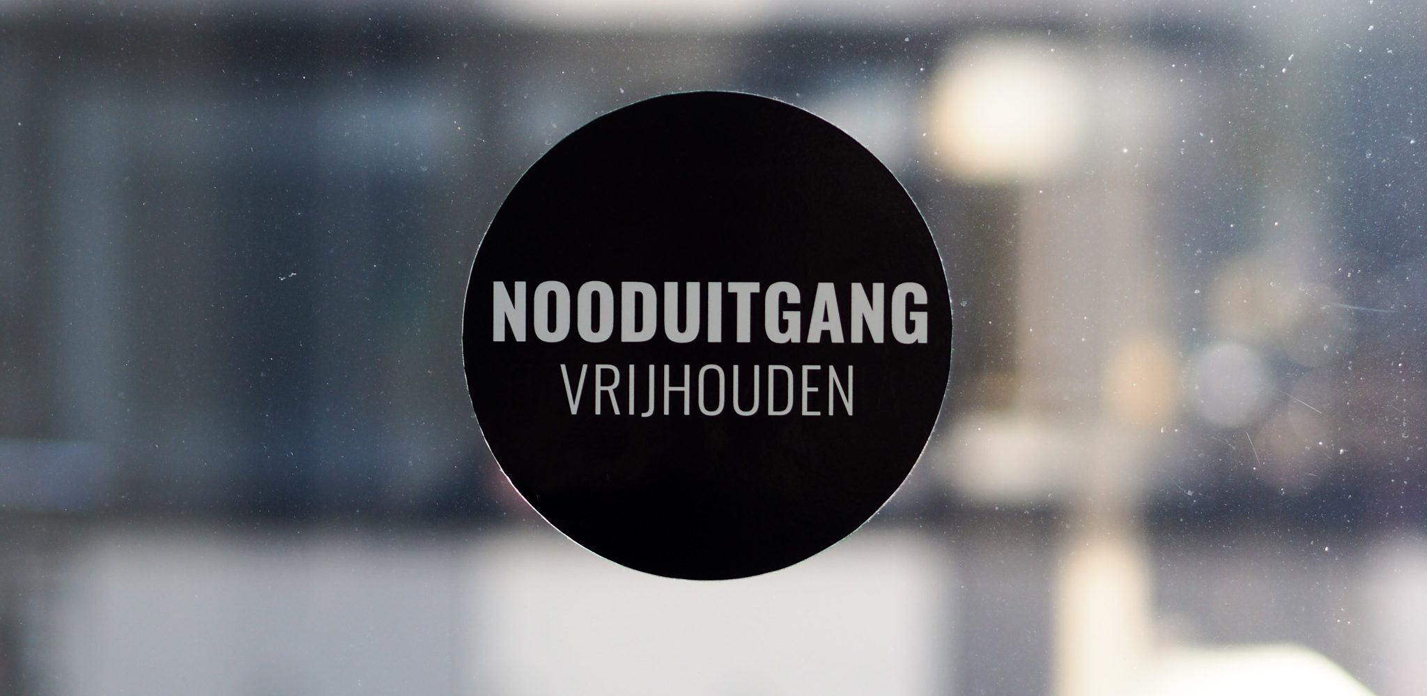 Ronde dubbelzijdige raamsticker zwart met nooduitgang